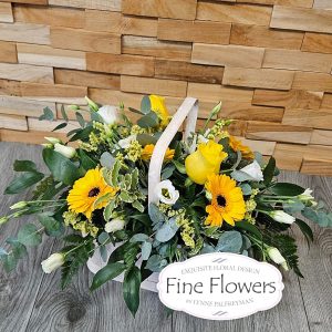A basket full of yellow flowers, including rose, gerbera, lisianthus, and solidago with mixed foliages to compliment