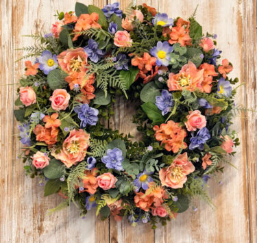 Coral Wreath featuring Hydrangeas, Cosmos, Roses, Delphinium, Mixed foliages including ferns and Eucalyptus.