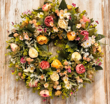 Peaches and Cream wreath featuring Ranunculus, Roses, Daisy’s, Thistle, Blossom, Mixed foliages including ferns and Eucalyptus.